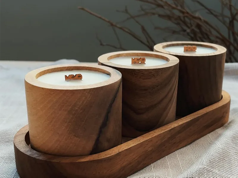 Trio de velas em potes de madeira sobre bandeja